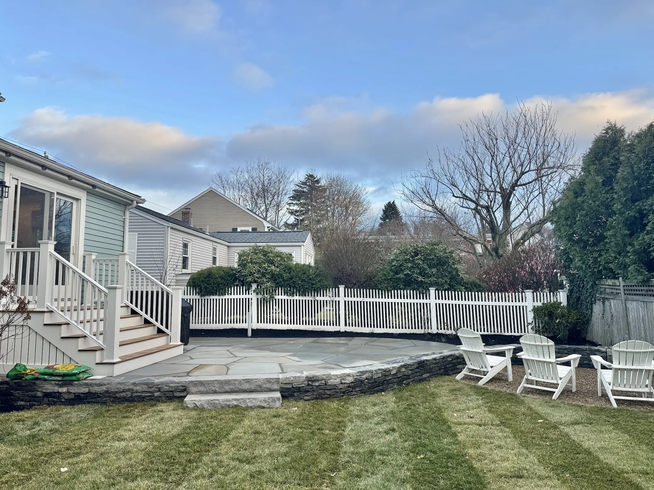 Raised irregular bluestone patio hardscaping with lawn and seating area by Lasana's Landscaping